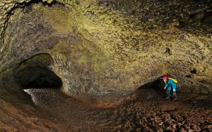 female caver in a braided passage with golden microbes