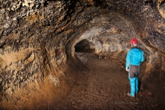 Caver in a passage, vandalism visible