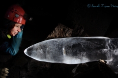 Caver looking at a bent ice stalagmite